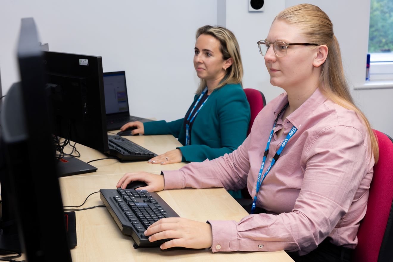 Two Female colleagues working on their desktop PC's in a office.