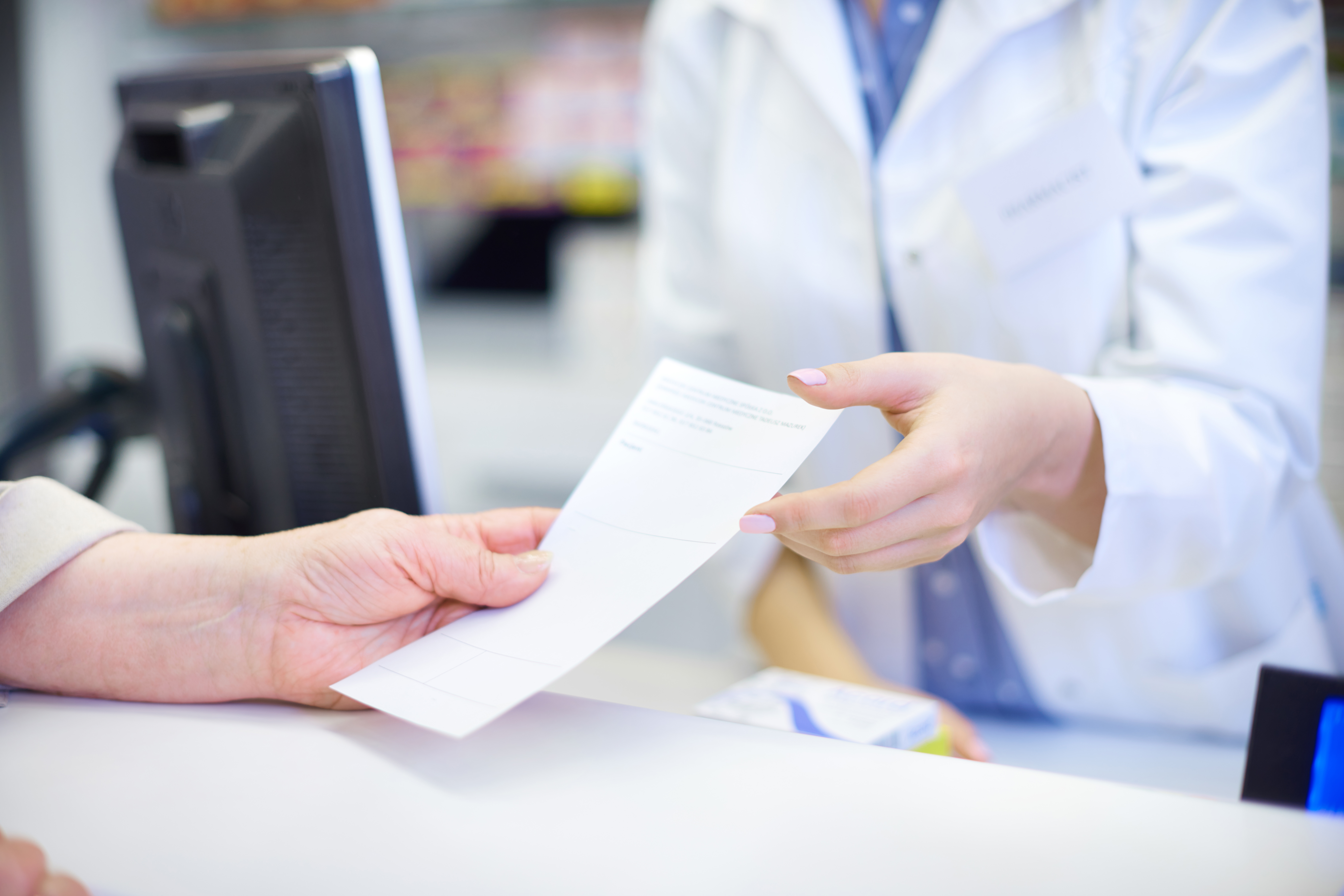 Close up of a patient being passed a prescription from a pharmacist