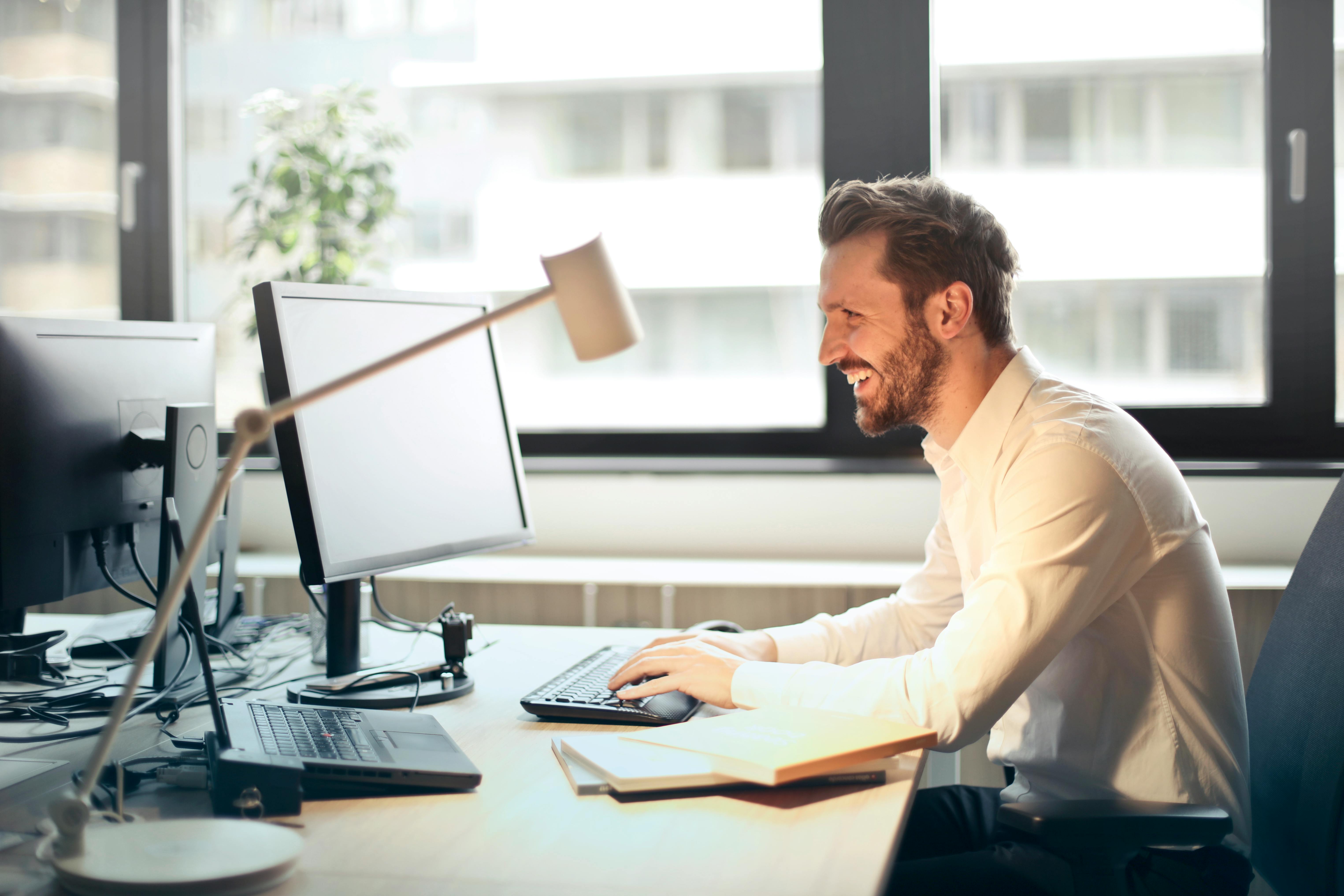 man smiling and typing on keyboard at desk