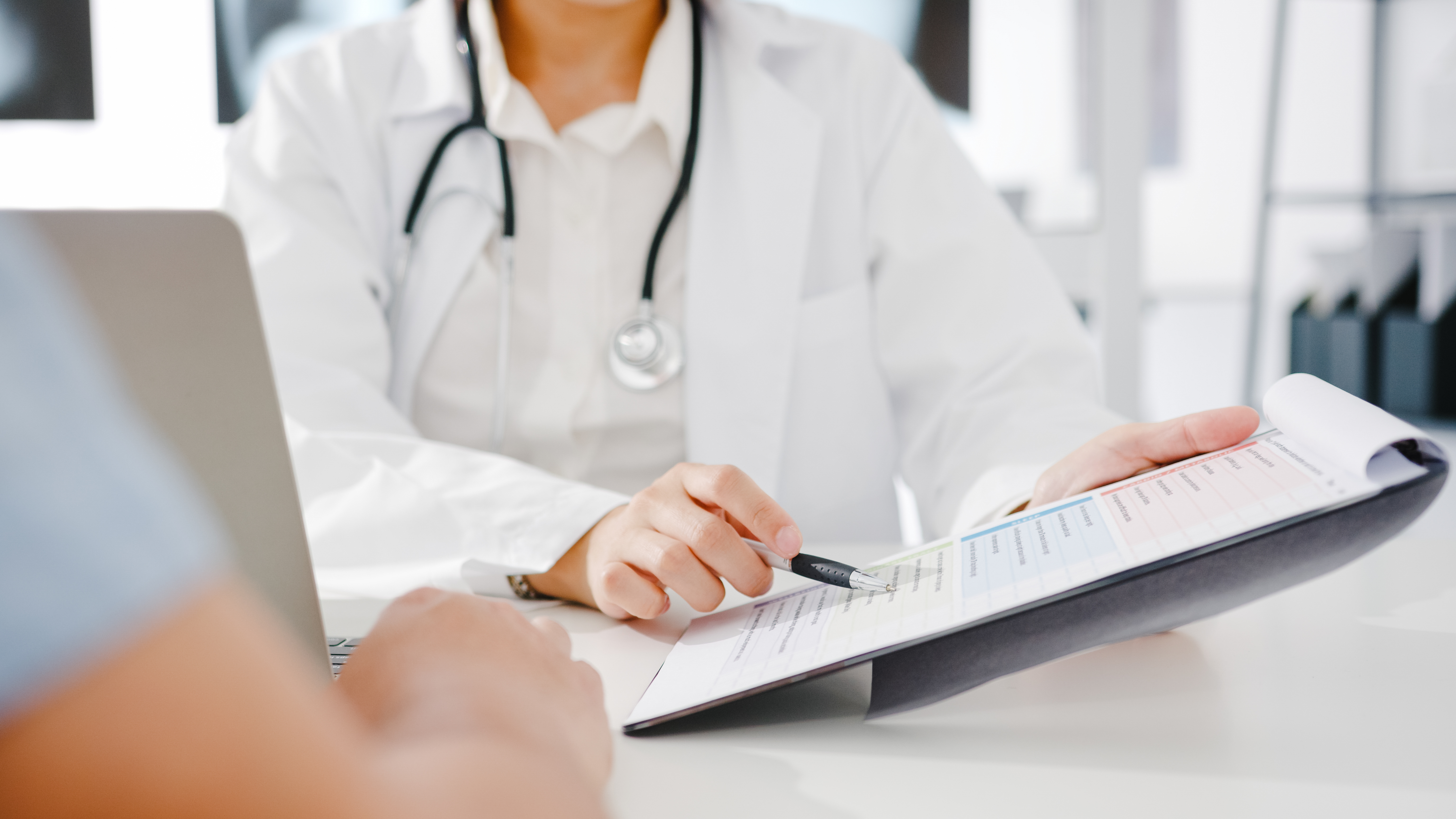 Young doctor working with pointing to a clipboard with a pen