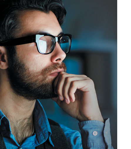 Male with glasses looking at a computer screen